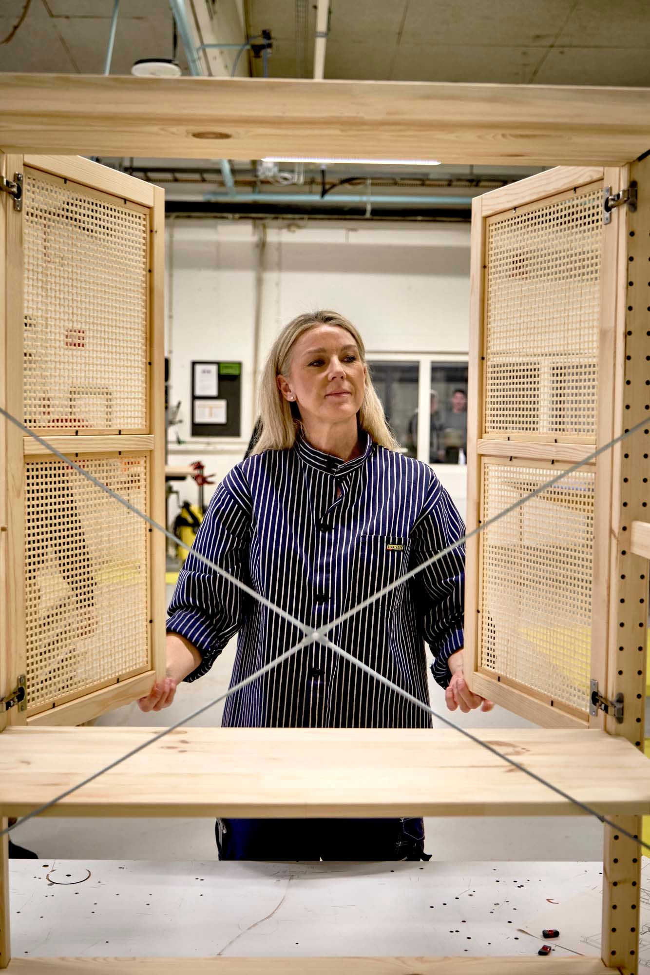 Designer Ebba Strandmark opens bamboo woven doors to a cupboard.