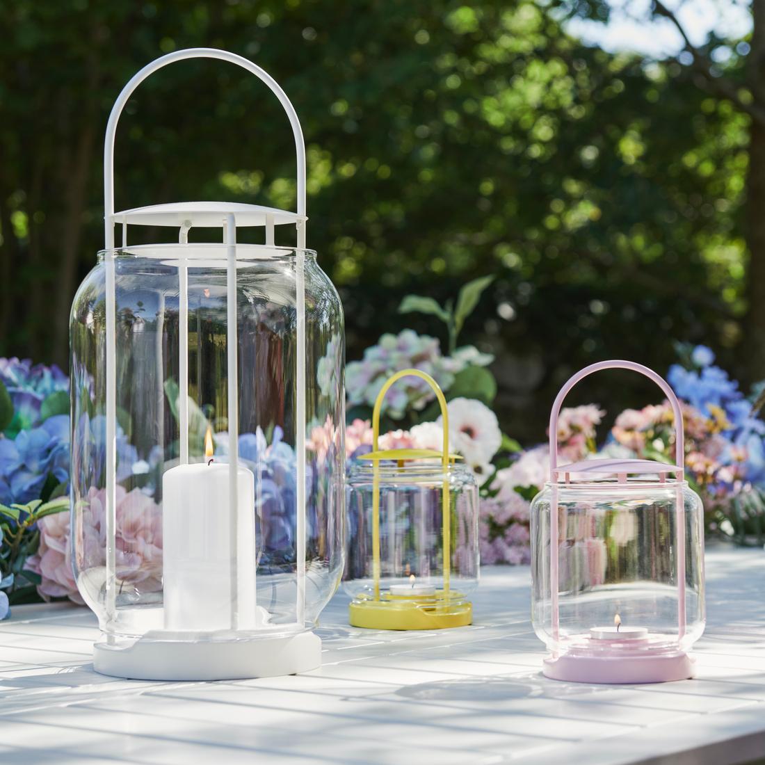 Outdoor dining table set with pastel tablecloth, bowls and glassware, decorated with sunflowers in a vase.