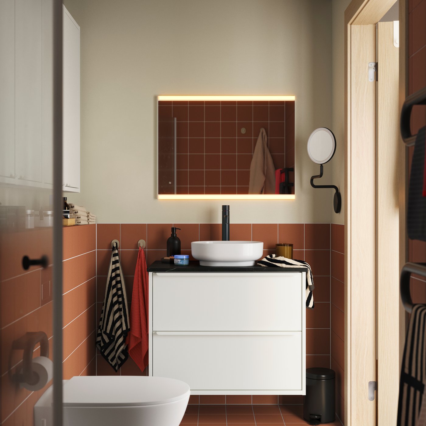 A terracotta-tiled bathroom with HAVBÄCK/VINDEÄLVEN washbasin cabinet in white, topped with a round basin and black tap.