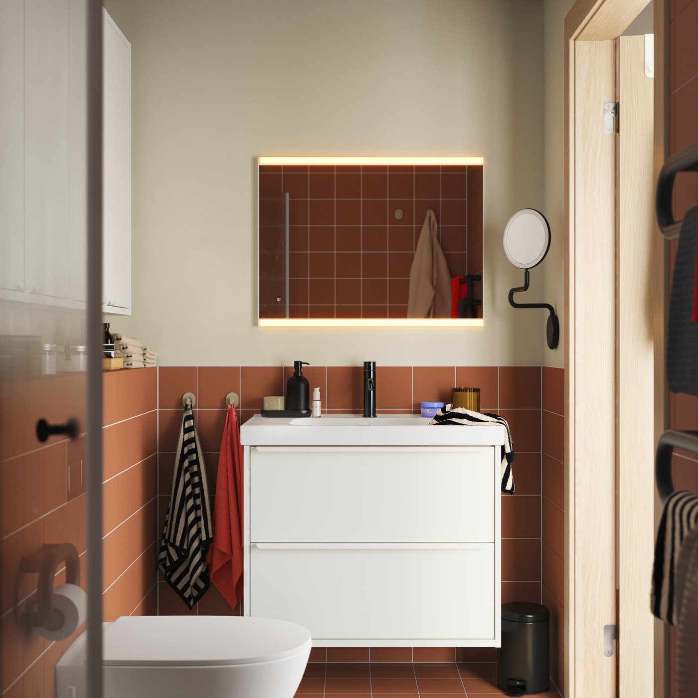 A terracotta-tiled bathroom with HAVBÄCK/ORRSJÖN washbasin cabinet in white, topped with a round basin and black tap.