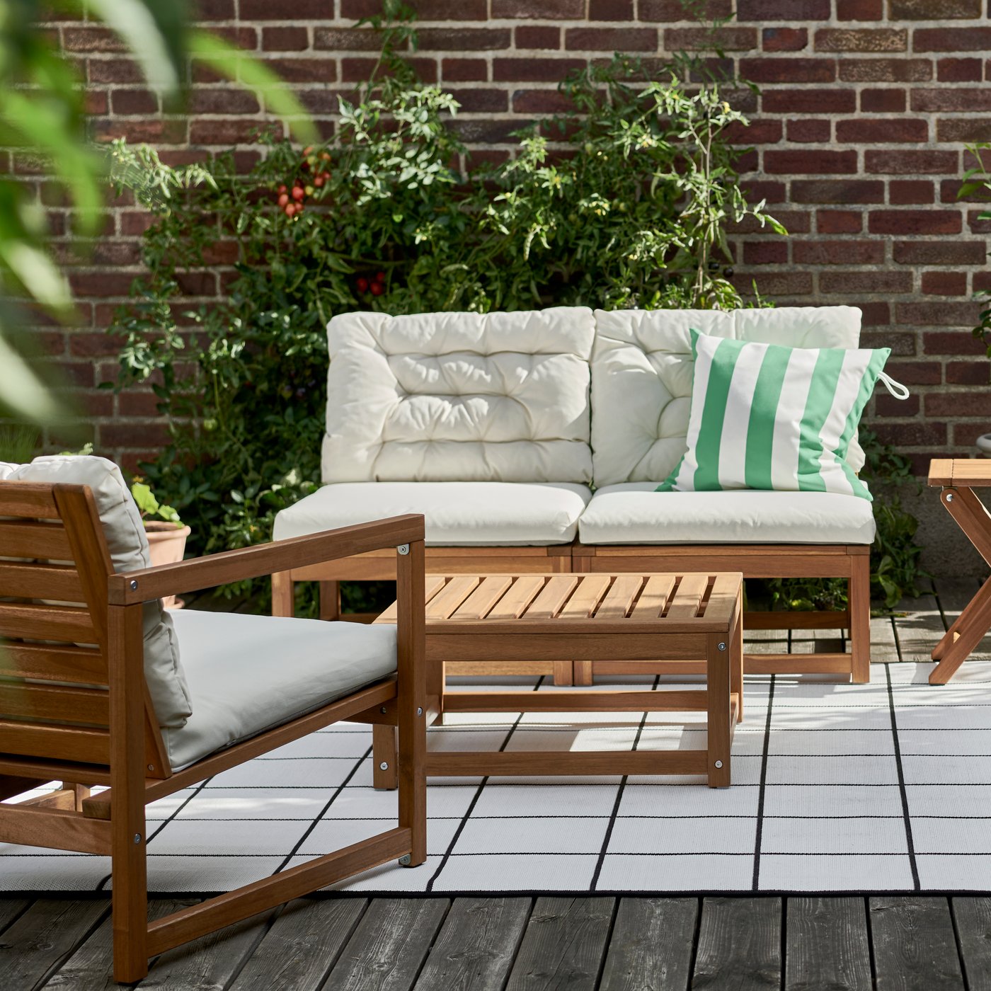 A NÄMMARÖ easy chair and a NÄMMARÖ sofa, with seat and back cushions, stand on a terrace on a sunny day.